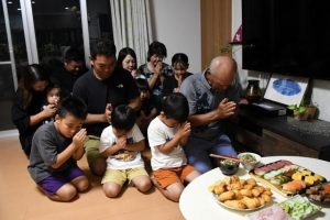 仏壇に料理などを供えて先祖の霊を迎える砂川家の皆さん＝４日、下地川満