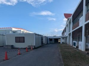 校舎(右)と体育館(奥)の間に設置されたプレハブ教室=10日、平良第一小学校