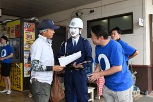 まもる君に扮し交通安全を呼び掛けチラシとステッカーを配布した＝９月30日、ＪＡファーマーズマーケットあたらす市場