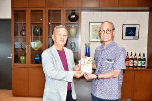 梅田さん（左）から嘉数市長に寄付金が手渡された＝10日、市役所