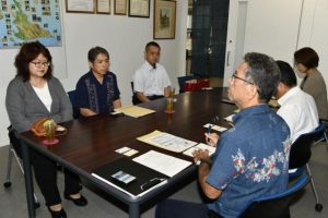 宮城教育長（右）に記念事業への協力を求める石嶺会長（左）、期成会副会長の濱元校長（同２人目）、下里善盛ＰＴＡ会長＝22日、市役所