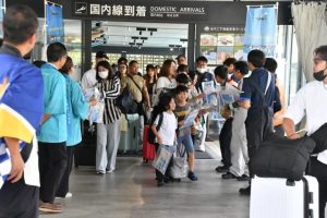 就航5周年の記念グッズを搭乗客に手渡した＝25日、下地島空港