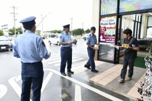 警察官が情報提供を呼び掛けるチラシを買い物客らに配布した＝20日、平良久貝タウンプラザかねひでみゃーく久松市場前