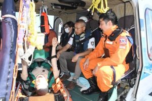 ヘリに乗り込み石垣航空基地の田尾拓海機動救難士（右）から説明を受ける打出医師（同２人目）ら＝30日、下地島空港