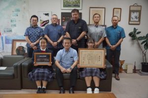 半嶺教育長(前列中央)に水大賞受賞と交際コンテスト参加を報告した本村さん(同右)と渡真利さん(同左)、船越校長(後列中央)、前里教諭(同右から2人目)ら=10月31日、県庁