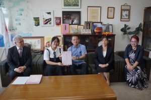 半嶺県教育長（中央）に出版した絵本を贈呈した上原さん（左から２人目）と母親の留美子さん（右）＝25日、県庁