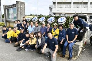 花鉢で埋め尽くされた看板と宮古島地区交通安全協会のメンバー、宮古島署員の皆さん＝29日、宮古島署