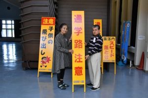 宮國会長（右）が砂川自治会長に立て看板を手渡した＝４日、城辺公民館