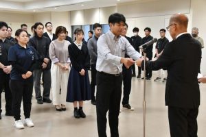 嘉数市長（右）から兼任辞令を受け取る職員＝22日、市役所