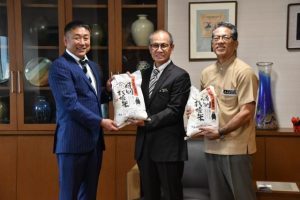 嘉数市長と宮城克典教育長に新米を手渡す立山代表理事（左）＝２日、市役所