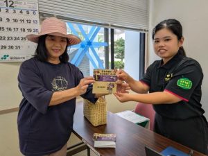 クーポン券を受け取り笑顔を見せる村民＝16日、村役場１階会議室