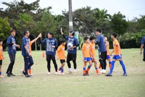 ゲームを終え子供たちとハイタッチする小野さん（中央）、上里さん（同左）ら ＝13日、平良前福多目的運動場