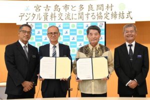 協定を締結した嘉数市長（左から２人目）、伊良皆村長（同３人目）＝23日、市役所