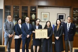 嘉数市長(左)、宮城教育長(右)に受賞を報告した饒平名会長(右3人目)と同協会のメンバー=19日、市役所