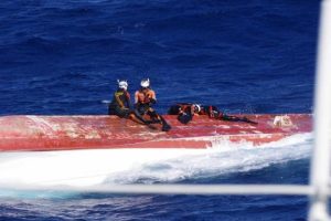 船底に移乗し打音確認する潜水士ら＝４日、宮古島南方沖（宮古島海上保安部提供）