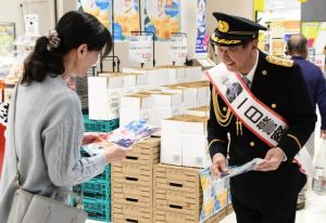 一日警察署長の森末さんが買い物客に１１０番の適正利用を呼び掛けるチラシを配布した＝10日、サンエー宮古島シティ