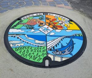 市制施行20周年を記念して設置されたマンホールふた＝17日、市公設市場前