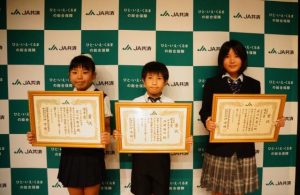 書道の半紙の部、交通安全ポスターの部でそれぞれ優秀賞を受賞した（右から）荷川取凛心さん、外間さん、荷川取結衣さん＝17日、那覇市の県立博物館・美術館の講堂