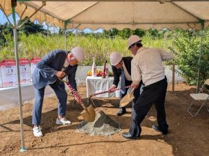 くわ入れを行い工事の安全祈願をする（左から）織部代表、長嶺社長、伊良皆村長＝13日、字塩川の建設予定地