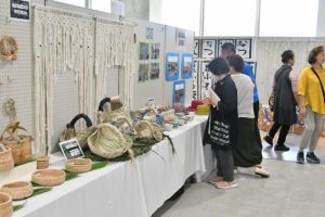 並べられた展示品を見る来場者ら＝22日、市未来創造センター