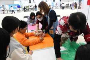 ポリ袋のポンチョづくりに挑戦する参加者たち＝７日、ＪＴＡドーム宮古島