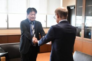 意見書などを手渡した兼島委員長と受け取る嘉数市長＝26日、市役所