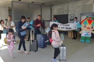 台中からの初便で到着した搭乗客を記念品や三線演奏などで歓迎した＝13日、下地島空港