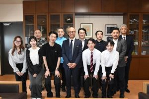 嘉数市長(前列右から3人目)を表敬訪問した5大学の(准)教授、学生ら=19日、市役所