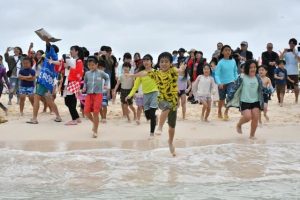 昨年の海びらきの様子。歓声を上げながら笑顔で海に走り出す子供たち＝２０２５年４月６日、与那覇前浜ビーチ