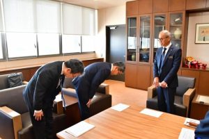 嘉数市長（右）に謝罪する沖電の阿波根氏（中央）と同社社員＝18日、市役所