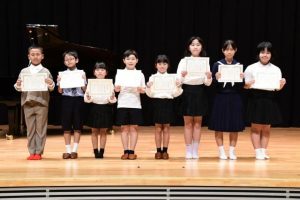 「三冠」受賞に輝いた與那覇晏理さん(右から4人目)ら入賞した児童生徒の皆さん=1日、市未来創造センター多目的ホール