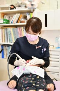 小さな子には声を掛け励ましながら治療する平安さん＝14日、ＫＡＺＵデンタルクリニック